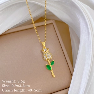 Close-up of a gold rose necklace with white and green crystals on a beige jewelry box