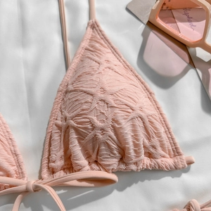 Detailed macro view of light pink bikini top featuring unique textured floral fabric