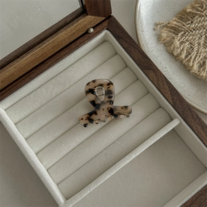 Detailed view of leopard acetate claw clip inside a beige velvet wooden jewelry box