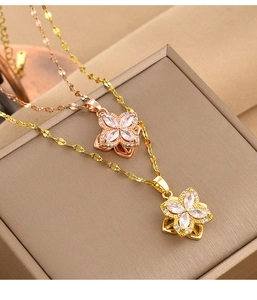 Close-up of gold and rose gold clover necklaces with sparkling zircons on a jewelry box