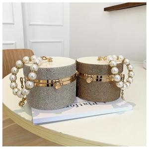Detail of silver and champagne gold cylinder clutch bags with rhinestones and pearl handle