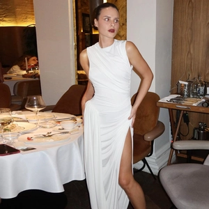 Detail van witte mouwloze geplooide maxi-jurk met zijsplit en een slanke pasvorm