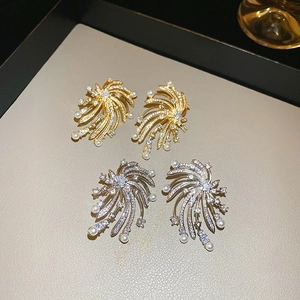 Detailed macro view of gold and silver starburst pearl earrings on a leather tray