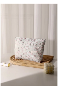 Close-up of gray floral storage bag with embossed texture and a small logo on wood tray