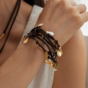 Vue détaillée du bracelet multi-rangs avec breloques goutte or et argent sur cordon brun