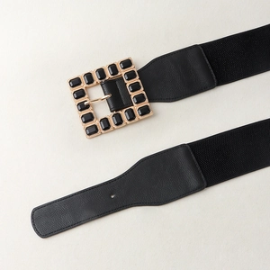 Detail of square gold buckle with black gems on a 6cm wide elastic waist belt