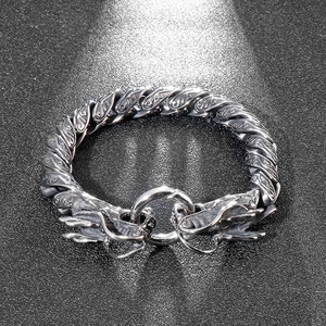Detail of vintage silver double dragon head bracelet with intricate scale engravings