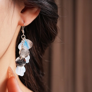 Gros plan de boucles d'oreilles à pampilles en nacre avec des détails de pétales blancs