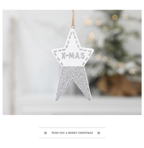 Close-up of wooden white star ornament with silver glitter and X-MAS carving