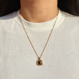 Vintage gold square pendant necklace with tiger eye stone worn on a white knit sweater