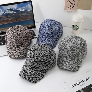 Detail view of four leopard print baseball caps in various colors on a white desk