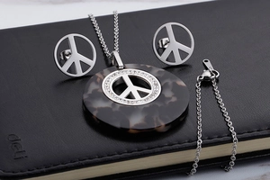 Detailed view of silver peace sign necklace and earrings set with tortoise resin and crystals