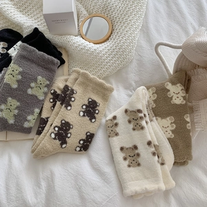 Flat lay of cozy teddy bear coral fleece socks in four colors on a warm bed