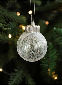 Detail of a transparent Christmas ornament with white mesh filling hanging on a tree