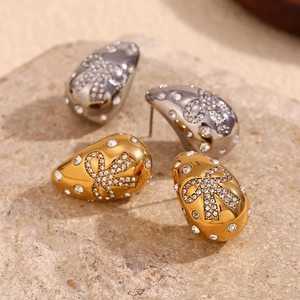 Macro view of gold and silver teardrop earrings with crystals and bow details