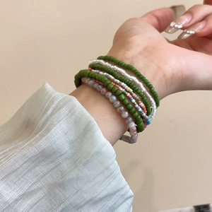 Detail of bohemian multilayer beaded bracelets in green and white on a woman's wrist
