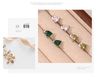 Detailed view of three-color triangular claw-set stud earrings in a beige velvet jewelry box