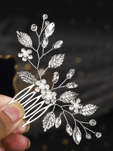 Macro detail of silver leaf hair comb featuring pearls and rhinestones for bridal styling