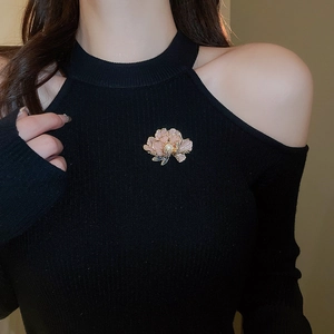 Close-up of a floral pearl brooch with pink gradient petals on a black sweater