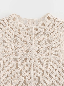 Vue détaillée du tricot au crochet beige montrant des motifs ajourés complexes