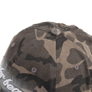 Close-up of 3D white embroidery on a washed camouflage baseball cap with twill fabric