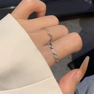 Close-up of stacked silver wavy and twisted rope rings with zircons on model's hand