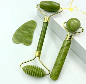 Detail view of green jade face roller and heart-shaped gua sha tool set with gold finish