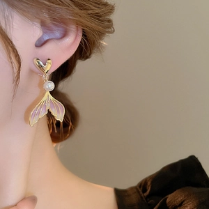 Close-up of mermaid tail pearl earrings with pink gradient and golden heart detail