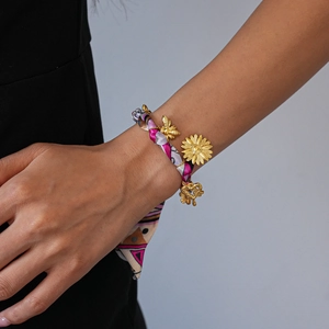 Detail of silk scarf bracelet with golden bee and sunflower pendants on wrist