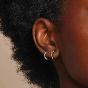 Close-up of gold hoop earrings with pave-set cubic zirconia on a model's ear