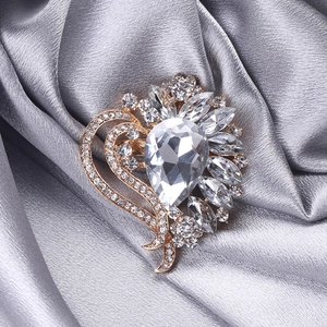 Macro detail of alloy heart brooch with teardrop crystal and marquise stones on satin