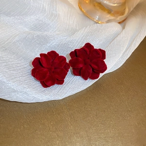 Vue macro de boucles d'oreilles fleurs floquées rouge foncé avec texture veloutée et argent