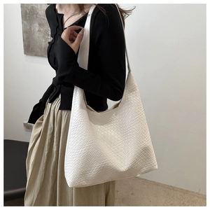 Detail of the white woven texture large tote bag shown on a model in a minimal setting