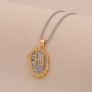 Close-up of golden letter H pendant necklace with sparkling diamonds on a bead chain