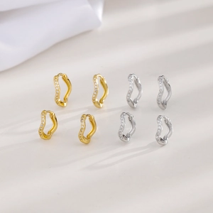 Macro detail of wavy hoop earrings with paved cubic zirconia in gold and silver