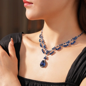 Detail shot of a vintage necklace with pear-cut deep blue gemstones and leaf design