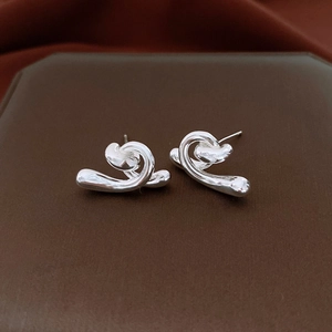 Detailed view of silver irregular twisted stud earrings on a brown jewelry display