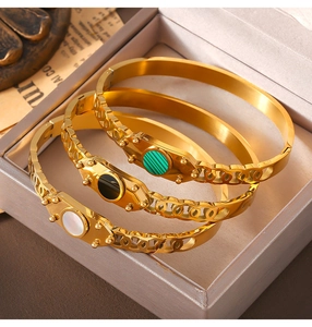 Detailed shot of three gold titanium bracelets with green, black, and white inlay accents
