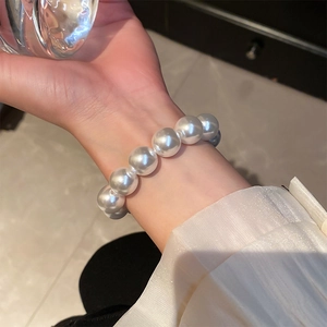 Close-up of elegant oversized white pearl elastic bracelet on wrist with soft glow