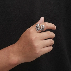 Detailed close-up of a vintage silver snake ring with textured scales on a thumb
