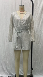 Detail of silver sequined long sleeve romper featuring a deep V-neck and sparkling finish