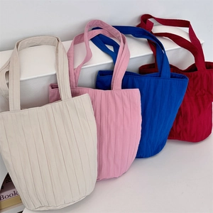 Detailopname van geplooide emmertassen in beige, roze, koningsblauw en donkerrood