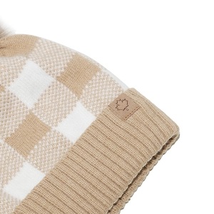 Close-up of beige checkerboard knit beanie with ribbed cuff and leather maple leaf patch