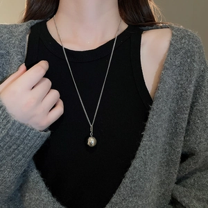 Close-up of minimalist silver ball pendant necklace worn on a model for a stylish look