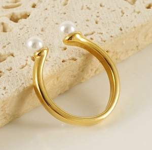 Vue détaillée d'une bague ouverte en acier doré 18k ornée de deux perles blanches élégantes