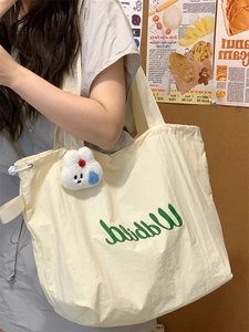 Detail of off-white tote bag with green Walnut print and cute bunny plush charm on strap