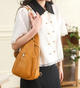 Detail of ginger PU crossbody bag with geometric woven strap and lychee texture