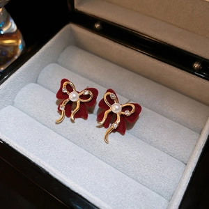 Detail of red flocked bow earrings with gold trim, pearl center, and sparkling rhinestones