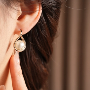 Detail view of a French vintage twisted metal earring featuring a teardrop pearl on model