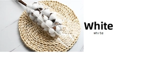 Close-up of dried cotton stems with fluffy white bolls on a rustic straw woven mat